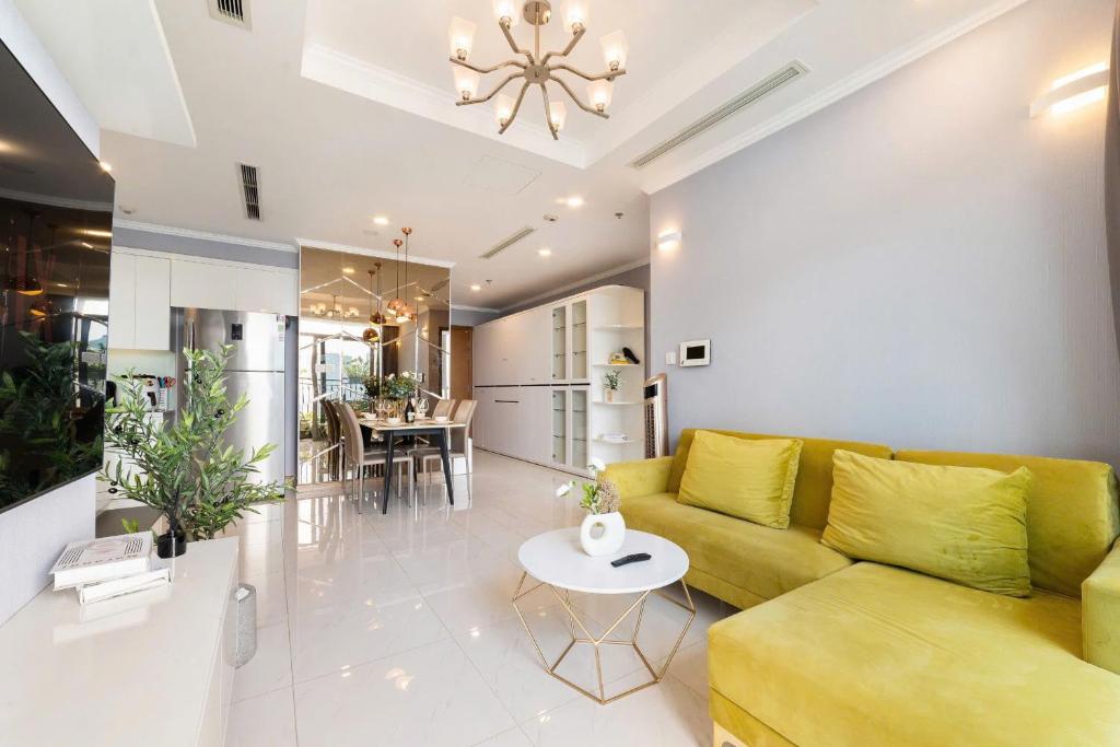 een woonkamer met een gele bank en een tafel bij Cozy Nest Vinhomes in Ho Chi Minh-stad