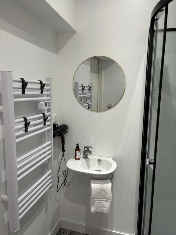 une salle de bain blanche avec un lavabo et un miroir dans l'établissement Au Tulipier, appartement 120m2, de 2 à 9 personnes, à Combeaufontaine