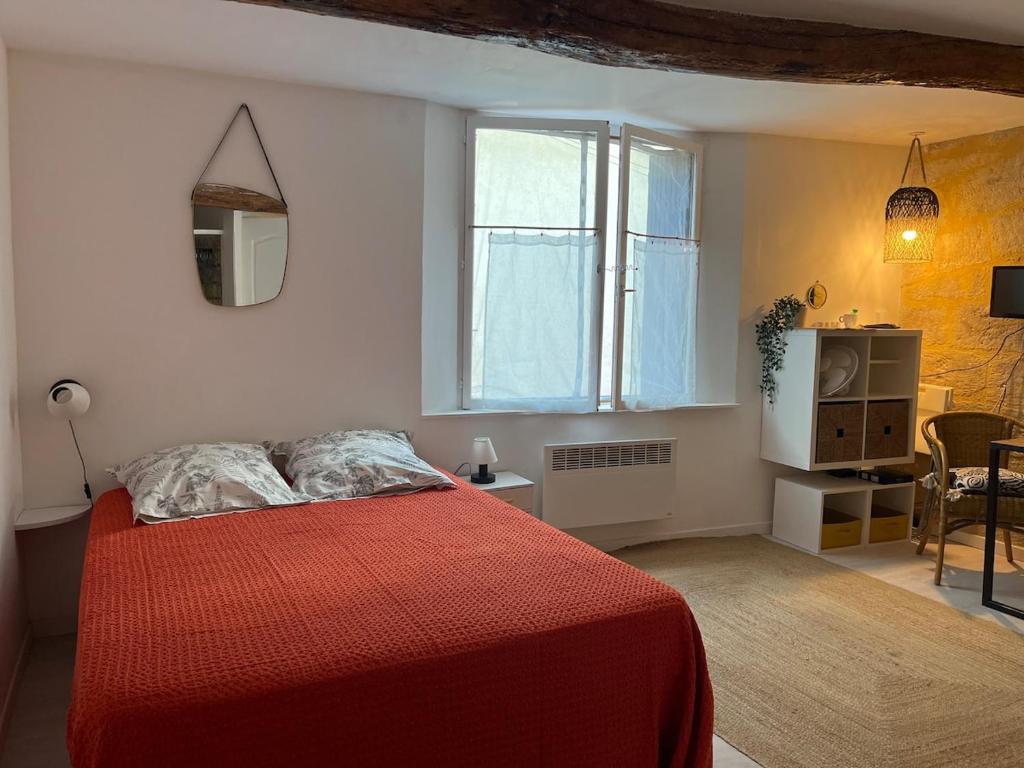 - une chambre avec un lit rouge et une fenêtre dans l'établissement Studio Cosy Rue piètonne calme Centre-ville d'Uzès, à Uzès