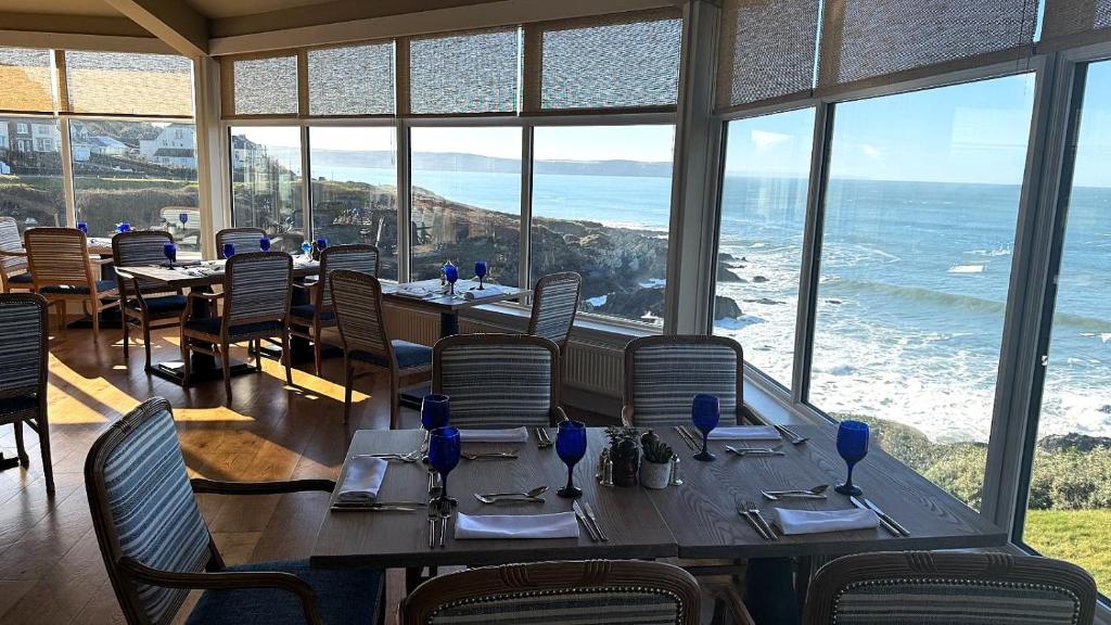 a restaurant with tables and chairs and a view of the ocean at Watersmeet Hotel in Woolacombe