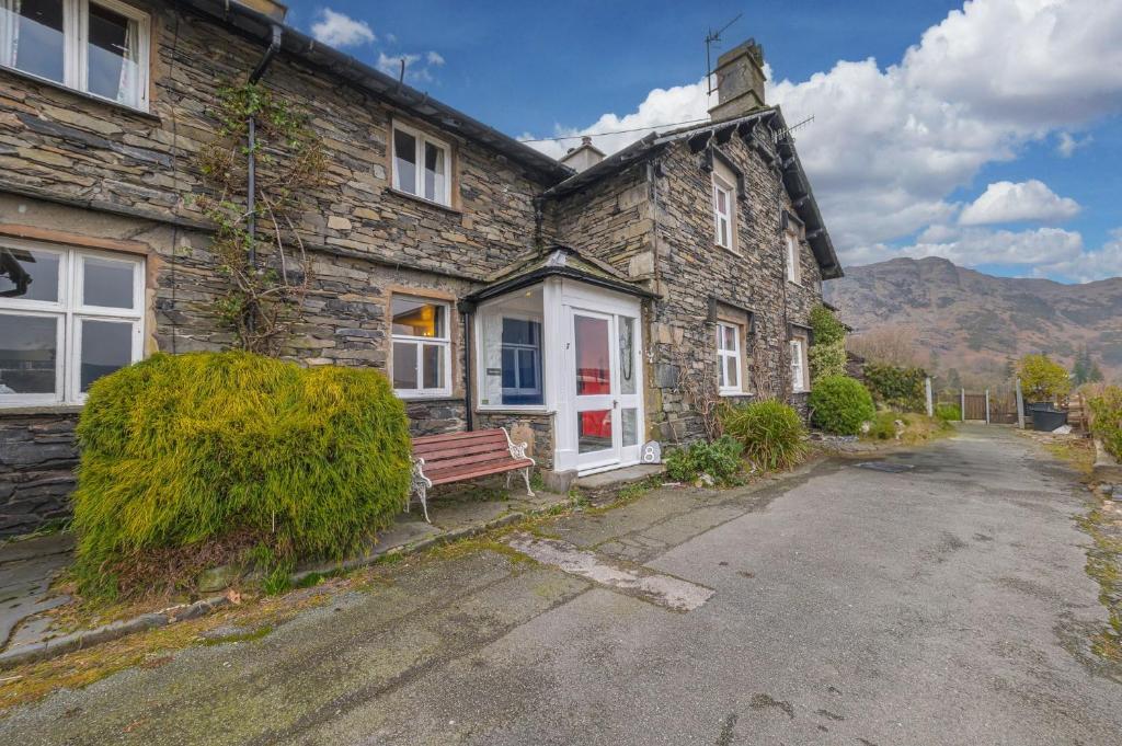 a stone house with a bench in front of it at Rose Bank Cottage Coniston in Coniston