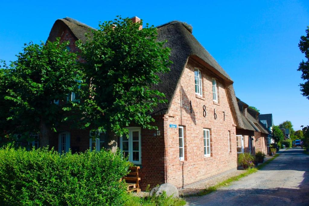 ein altes Backsteingebäude mit einem Strohdach in der Unterkunft Haus Boldix Whg 4 Cayman in Boldixum