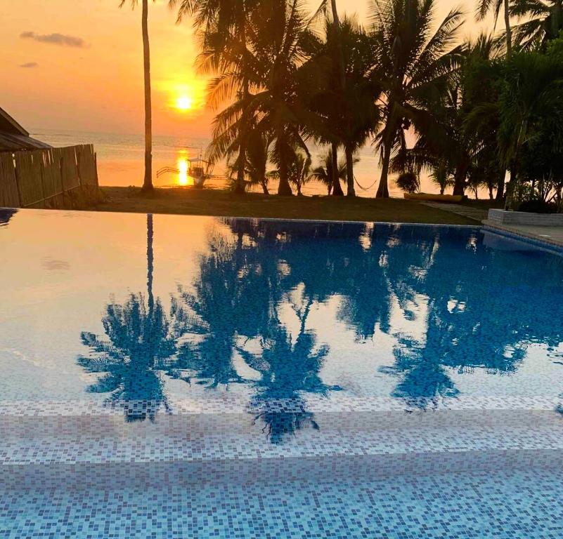 a swimming pool with a reflection of the sunset at OcamOcam Sunset-Bay Guest House in Busuanga