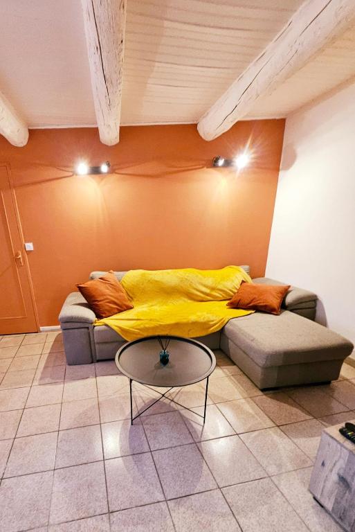 Cette chambre dispose d'un canapé avec une couverture jaune. dans l'établissement Charmant T2 des bourgades, à Caumont-sur-Durance