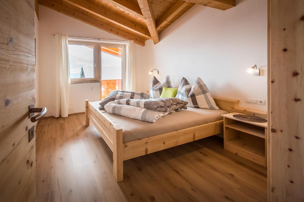 a bedroom with a wooden bed with a window at Nockhof in Terfens