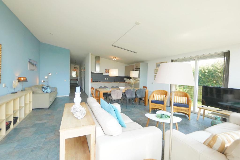 Una sala de estar con un sofá blanco y una cocina. en Beachlife 9, en Callantsoog
