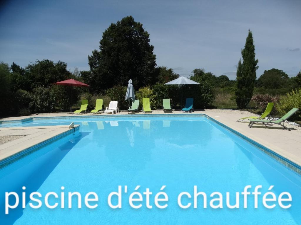une grande piscine avec chaises et parasols dans l'établissement La Petite Grange gîte climatisé plain-pied 3 chambres 5 personnes 2 toilettes parking WIFI piscine d'été chauffée animaux acceptés Gîte en pleine nature, à Lorignac