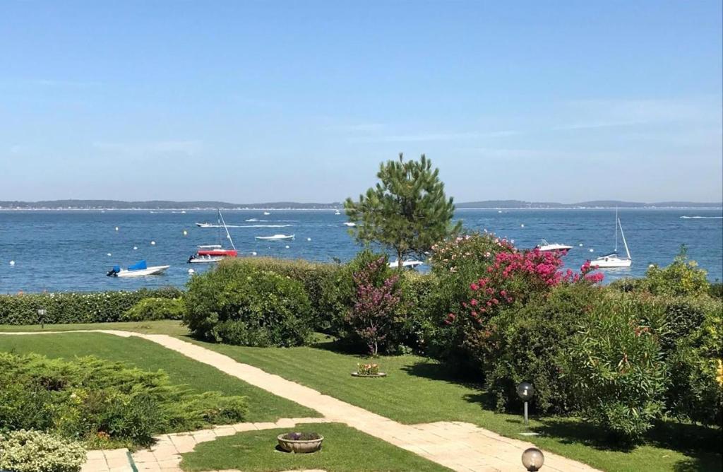 d'un jardin avec vue sur l'eau et les bateaux. dans l'établissement Arcachon Plage Pereire, à Arcachon