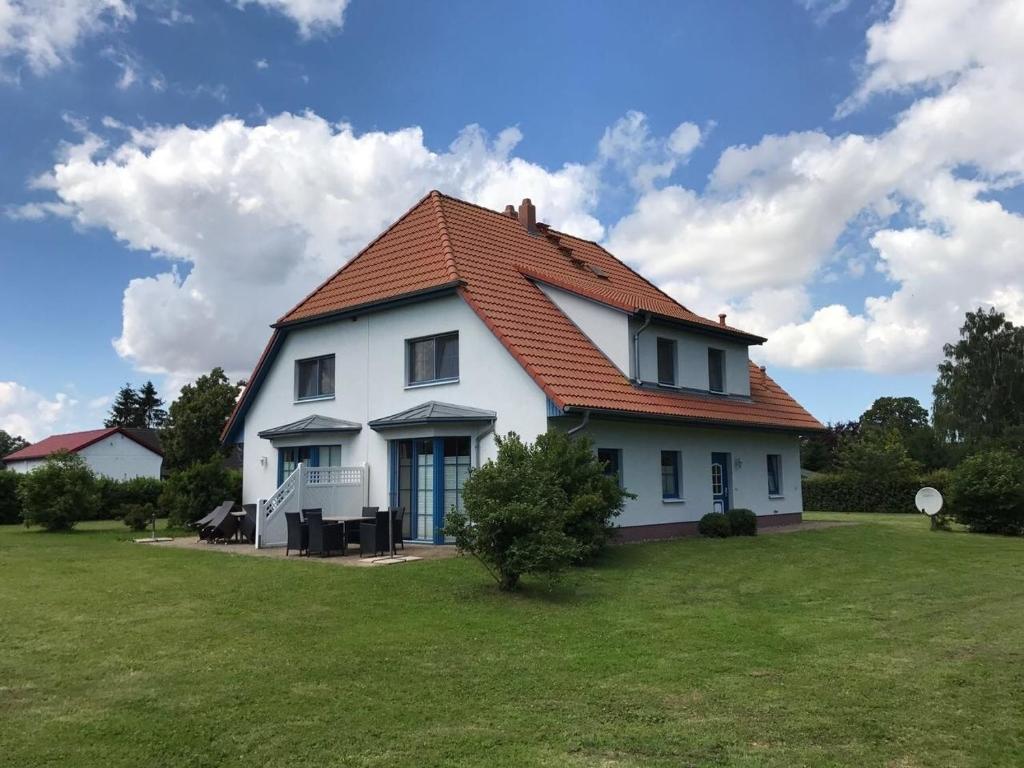 a white house with an orange roof on a field at Dycke Haus 6 in Garz-Rügen