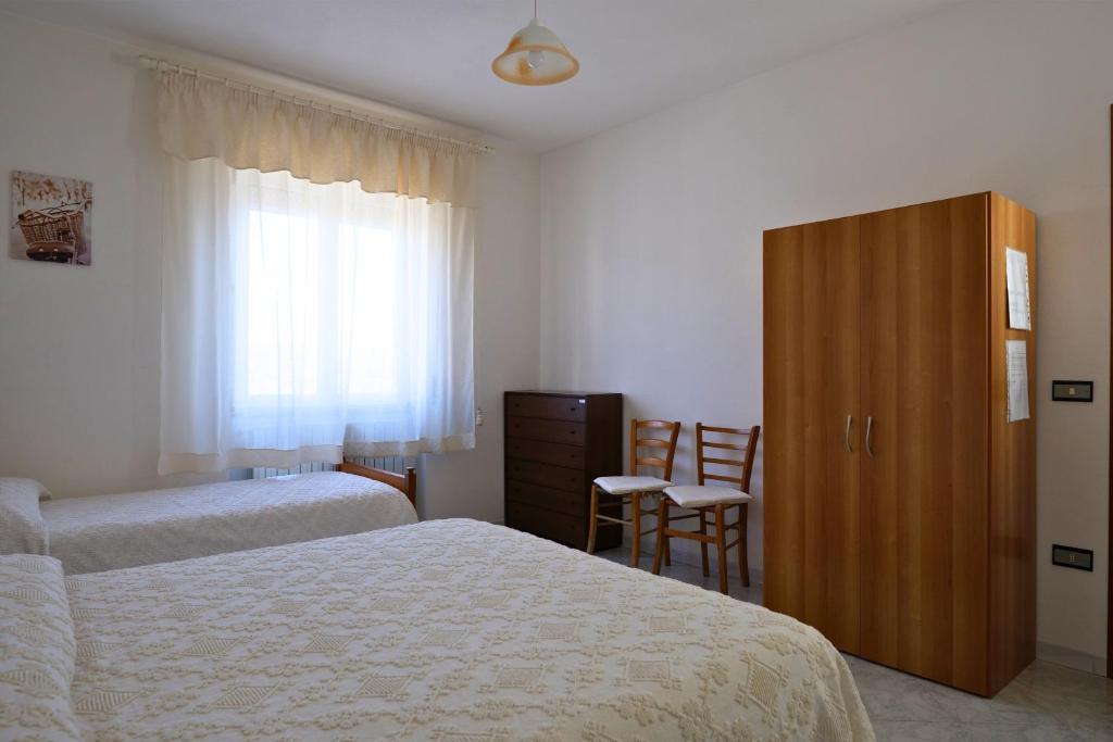sypialnia z 2 łóżkami, szafką i oknem w obiekcie L Agrifoglio di Rita Loddo w mieście Fonni