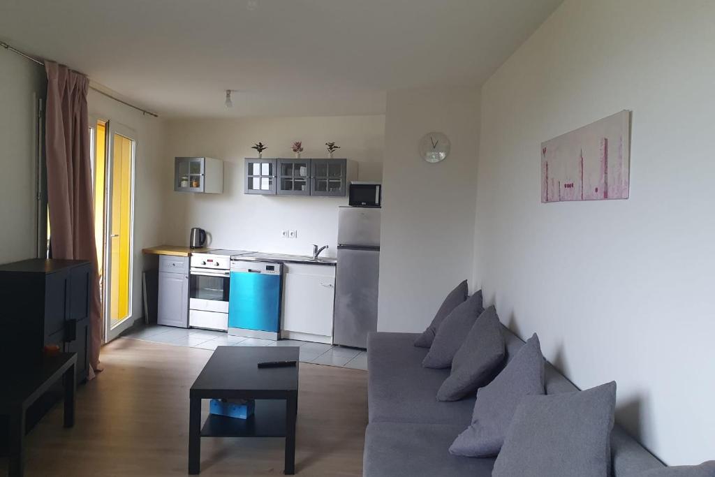 un salon avec un canapé et une cuisine dans l'établissement Charming T3 with balcony near Paris, à Villejuif