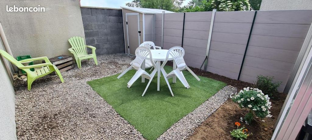 a patio with a table and chairs in a backyard at Maison Sabline 3 - T2 avec terrasse et parking 700m de l'océan - bébé bienvenu in Yves