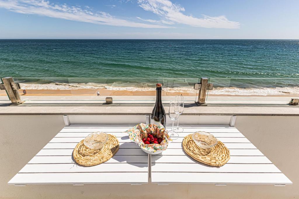 a table with a bottle of wine and a bowl of fruit at CoralMar Beachfront Apartment -Stunning Ocean Views -Algarve in Armação de Pêra