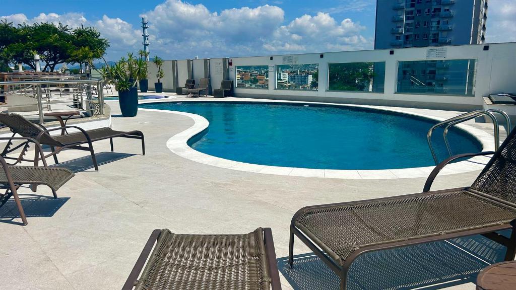 a swimming pool with chairs and a table and a building at Condomínio próximo a ponte Hercílio Luz in Florianópolis