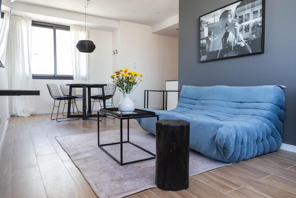 Una sala de estar con un sofá azul y una mesa. en Perla Beautiful Apartment, en Buenos Aires