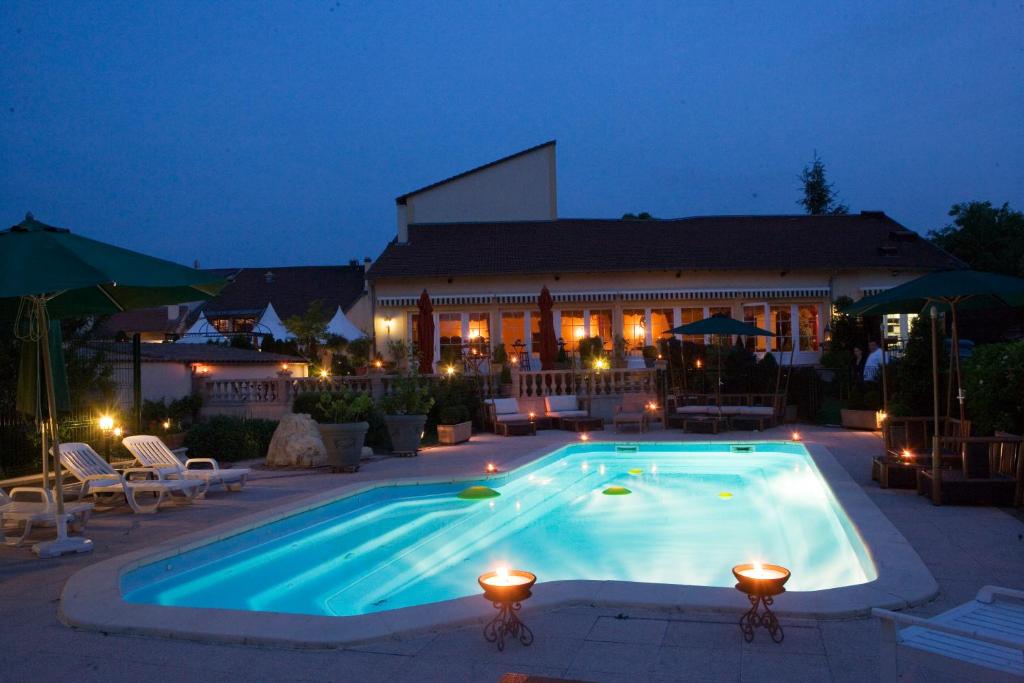 uma piscina à noite em frente a um edifício em Hôtel du Domaine de La Grange de Condé em Condé-Northen