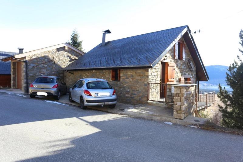 deux voitures garées devant une maison en pierre dans l'établissement Location magnifique chalet pour 10 personnes, aux Angles