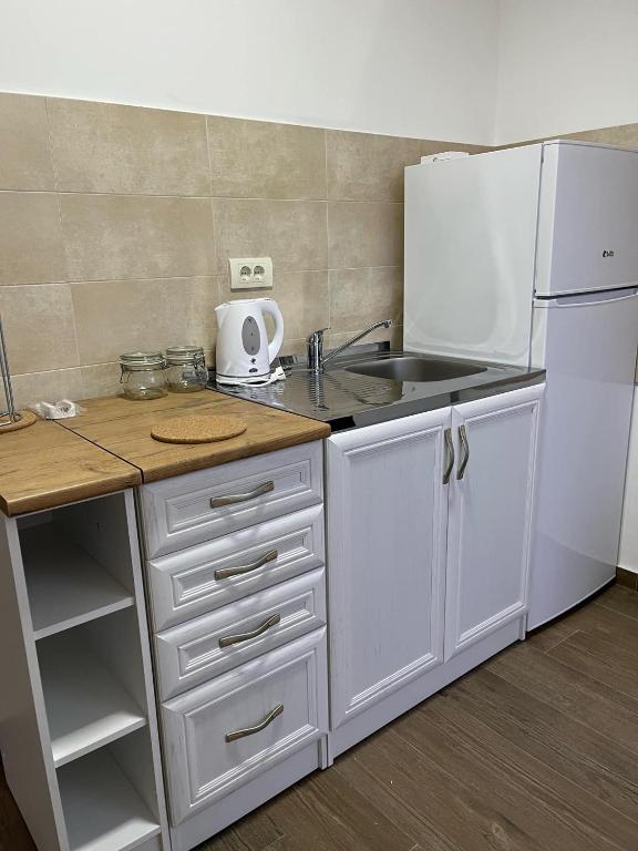 a white kitchen with a sink and a refrigerator at Mimura stan in Belgrade