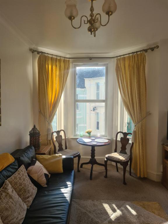 een woonkamer met een bank, een tafel en een raam bij Spacious two bedroom flat, central location in Plymouth