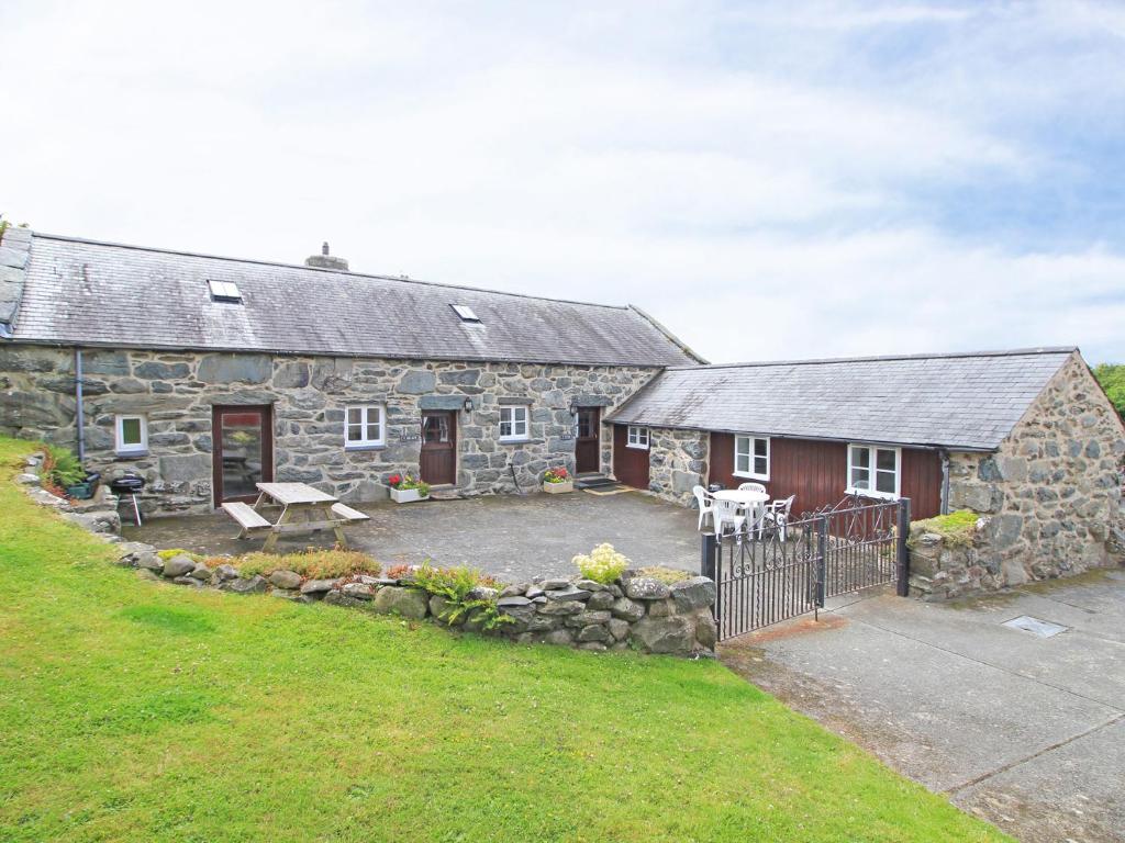 an old stone house with a patio in front of it at Y Stabl The Old Stable in Llanbedr