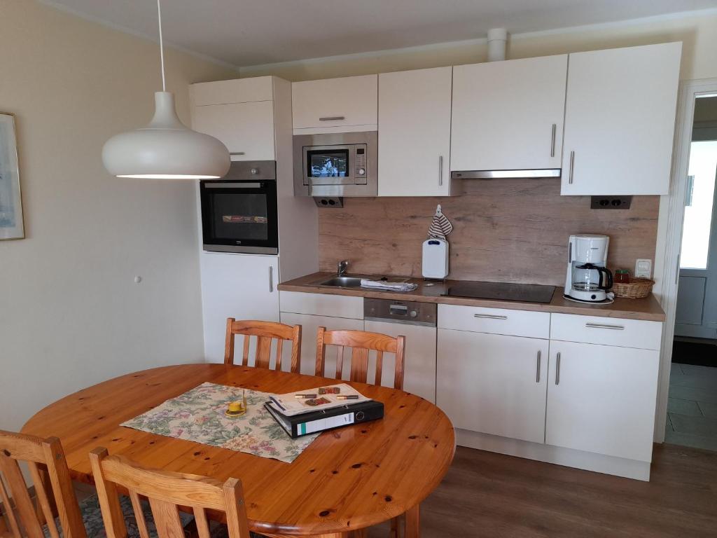 a kitchen with a wooden table and a kitchen with white cabinets at "Höper Mittelhof" Ferienhaus Nr3 in Lemkendorf