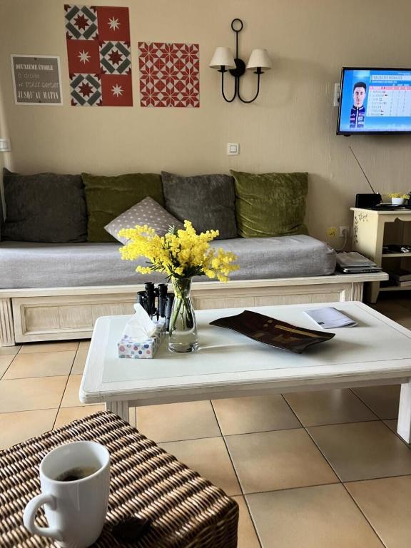 un salon avec un canapé et une table avec des fleurs dans l'établissement Les Appartements aux Restanques du Golfe de St Tropez - maeva Home - Appartement belle vue mer 3 pièces 7 personnes - Sélection MAE-1794, à Grimaud