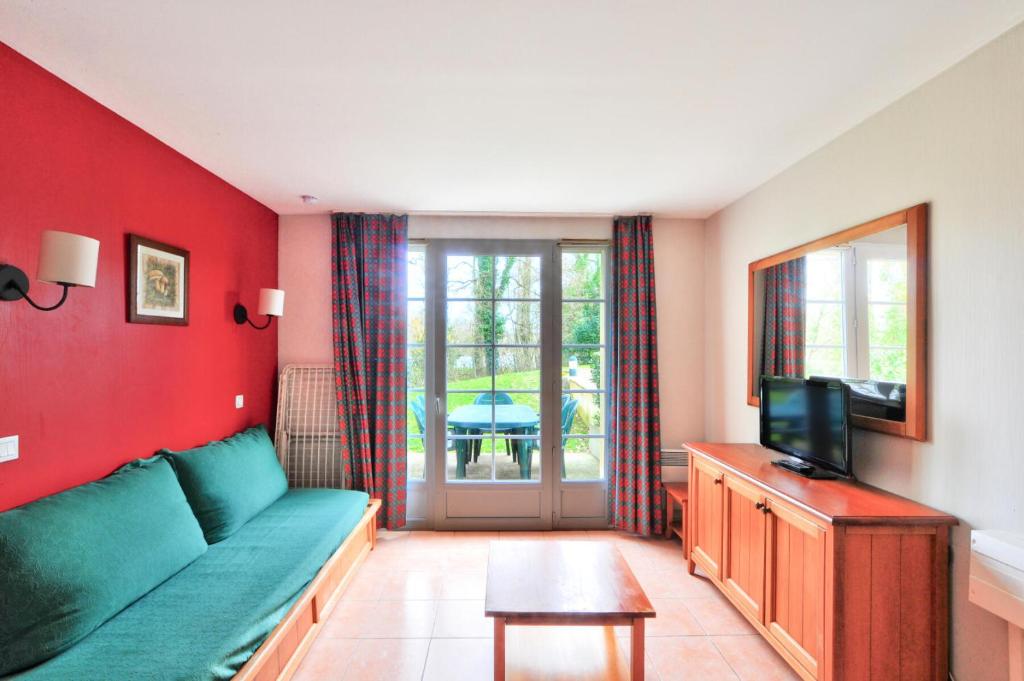 un salon avec un canapé vert et une télévision dans l'établissement La résidence du Lac - maeva Home - Maison 3 pièces 6 personnes - Sélection MAE-3941, à Monflanquin