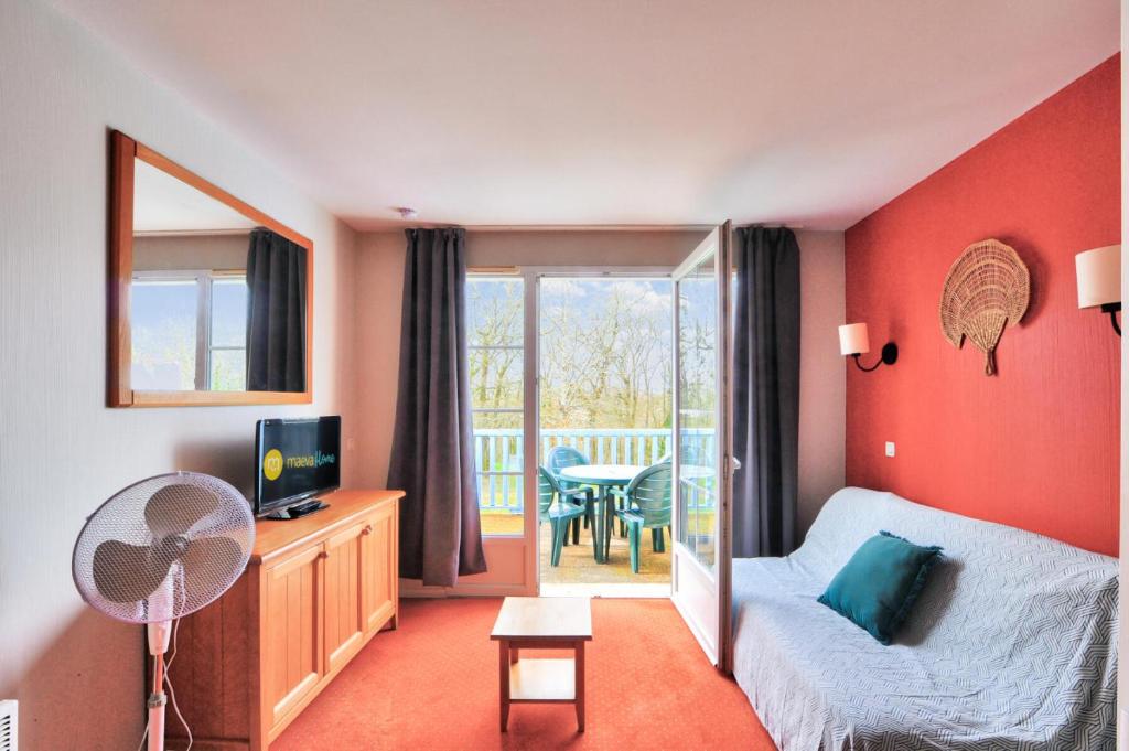 une chambre avec un lit et une télévision et un balcon dans l'établissement La résidence du Lac - maeva Home - Appartement 2 pièces 4 personnes - Sélection MAE-5761, à Monflanquin