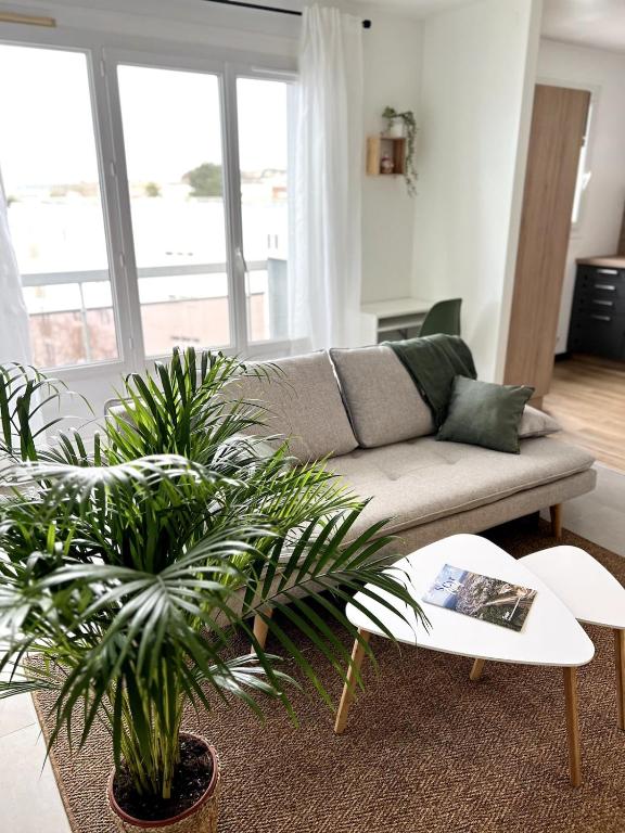 - un salon avec un canapé et deux plantes dans l'établissement Le sourire Saint-cyrien, à Saint-Cyr-lʼÉcole