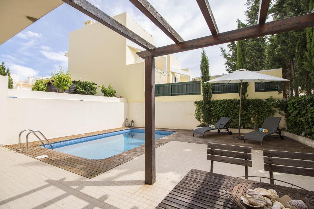 a patio with a swimming pool and an umbrella at Casa Oliveira in Loulé