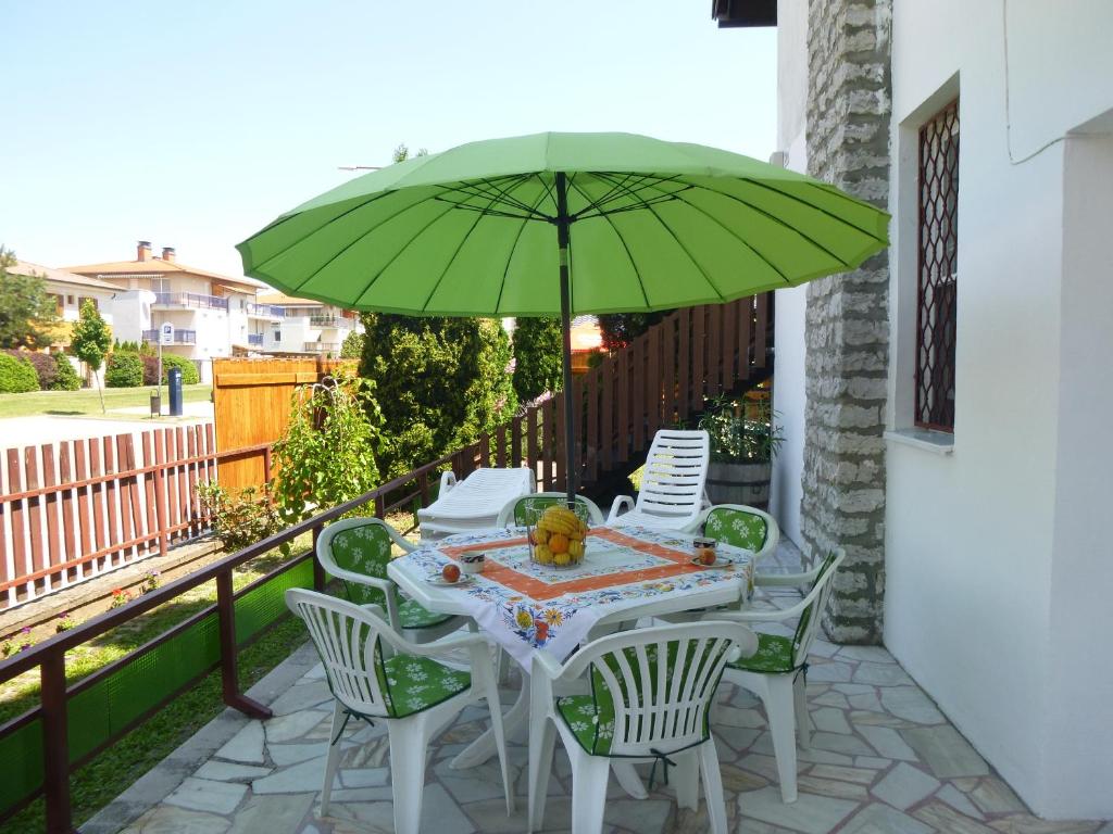 uma mesa e cadeiras com um guarda-sol verde numa varanda em Oleander Holiday House em Siófok