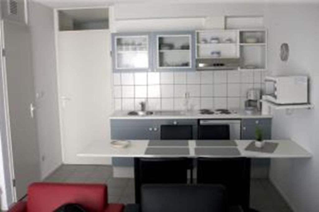 a white kitchen with a counter and a red chair at Ferienhaus 702 in Tossens in Stick