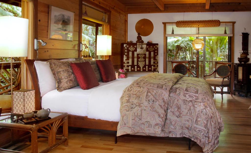 un hombre acostado en una cama en una habitación en Lotus Garden Cottages, en Volcano