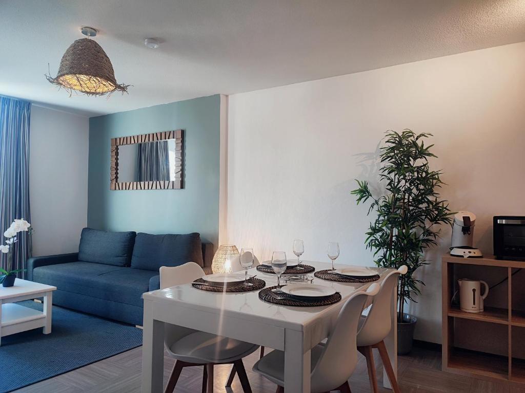 een woonkamer met een witte tafel en een blauwe bank bij L'Olivier - Piscine et climatisation in Gréoux-les-Bains
