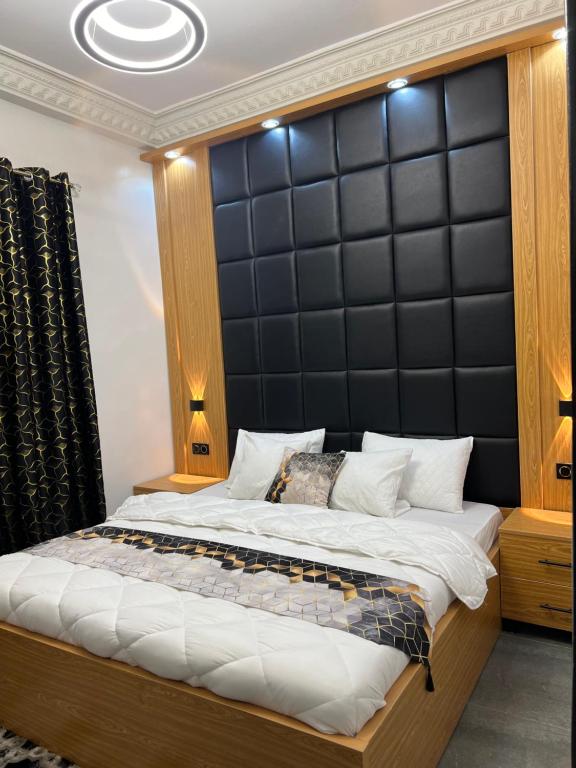 a bedroom with a large bed with a black padded headboard at Luxueuse petite chambre, salle de bain extérieure privée in Dakar