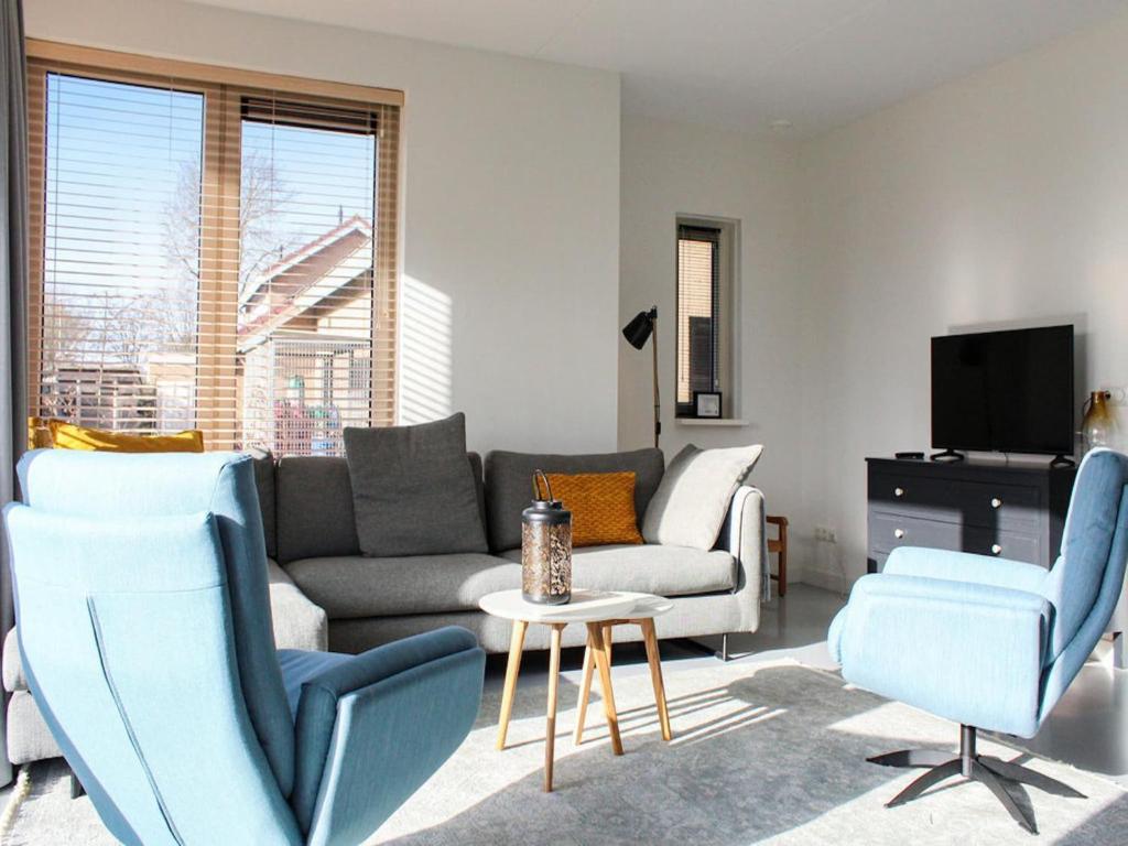 a living room with a couch and chairs and a tv at Villa in Friesland with Jetty and Fenced Garden in Idskenhuizen