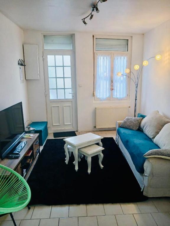 un salon avec un canapé bleu et une table basse dans l'établissement Maison de pêcheur la CORBOE, à Étaples