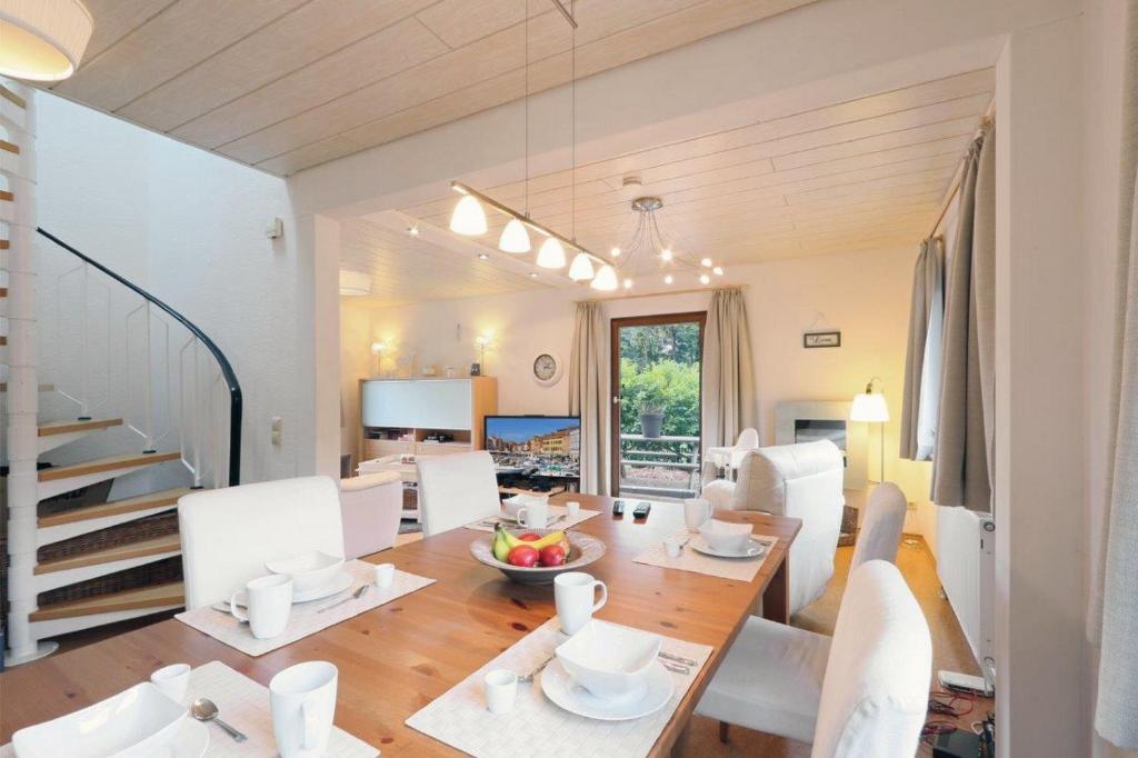 a dining room with a table and white chairs at Ferienhaus Anne mit Sauna, See, Wald und Ruhe in Kemmerode