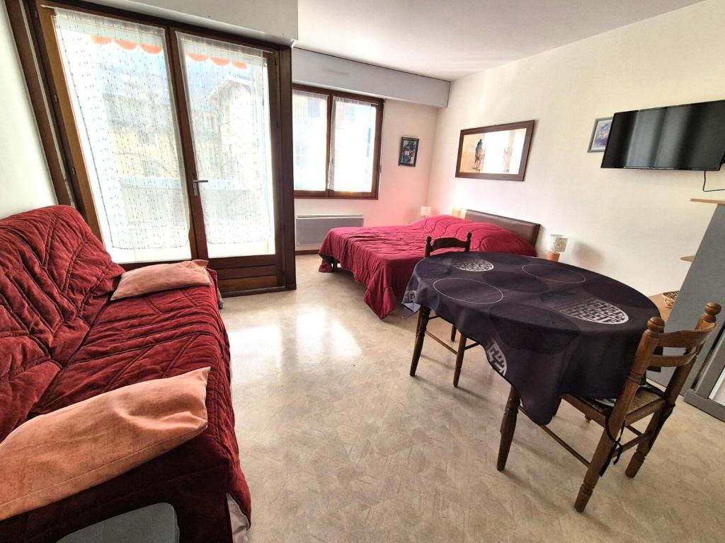 Cette chambre comprend 2 lits, une table et une télévision. dans l'établissement Résidence Le Chateau Durieux 2 - Agréable logement rénové ! MAE-7374, à Aix-les-Bains