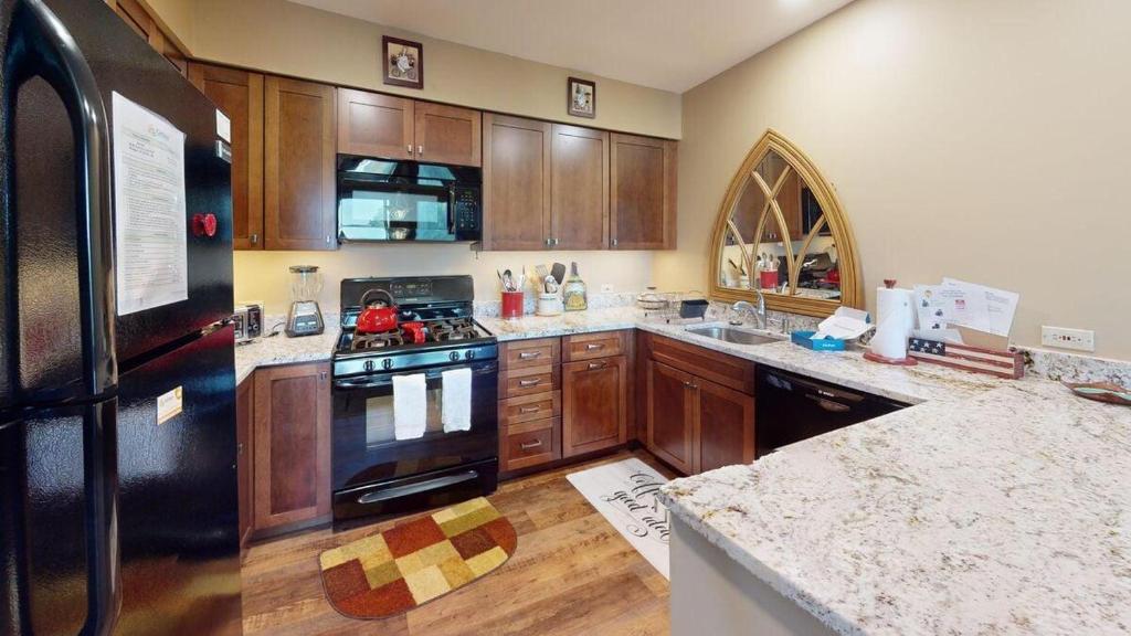 a kitchen with wooden cabinets and a black refrigerator at Sunrise - W Glade K-5 in Killington
