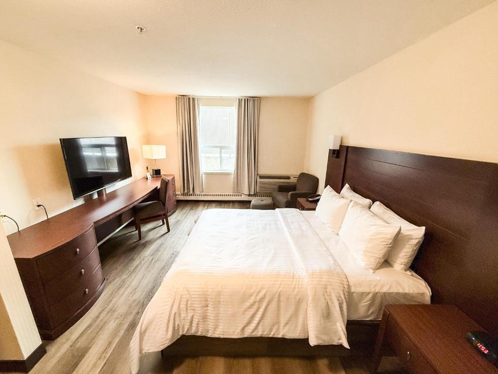 a hotel room with a bed and a desk and a television at West Edmonton Mall Inn in Edmonton