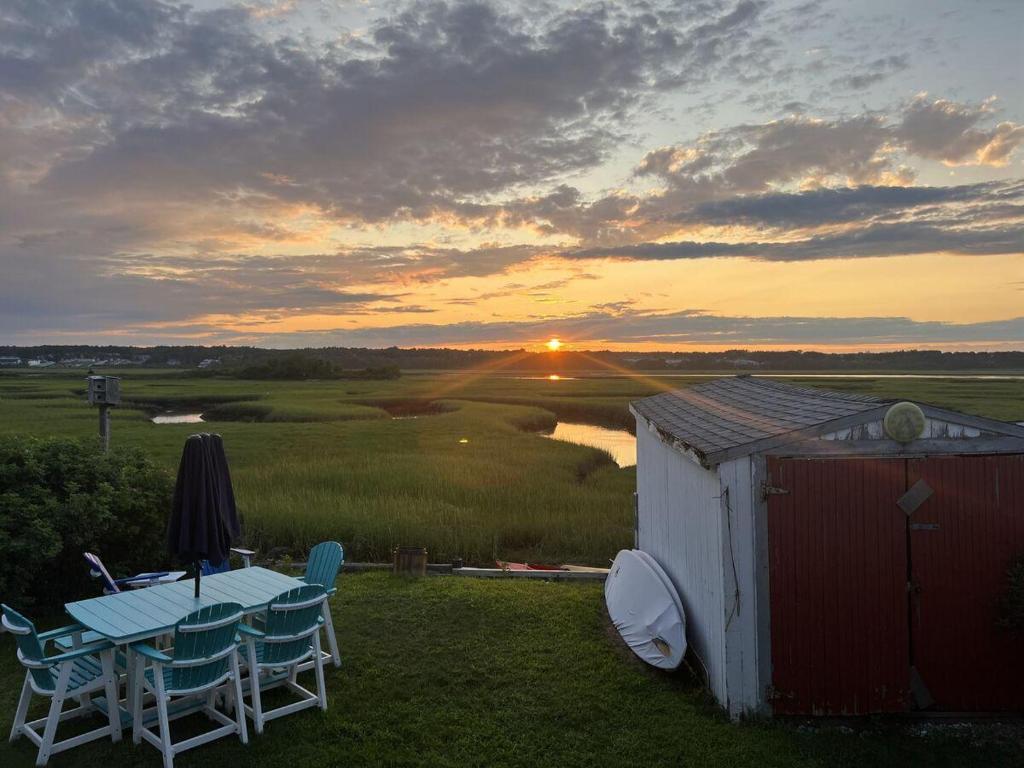 a table and chairs on a field with a sunset at Sea Esta in Wells