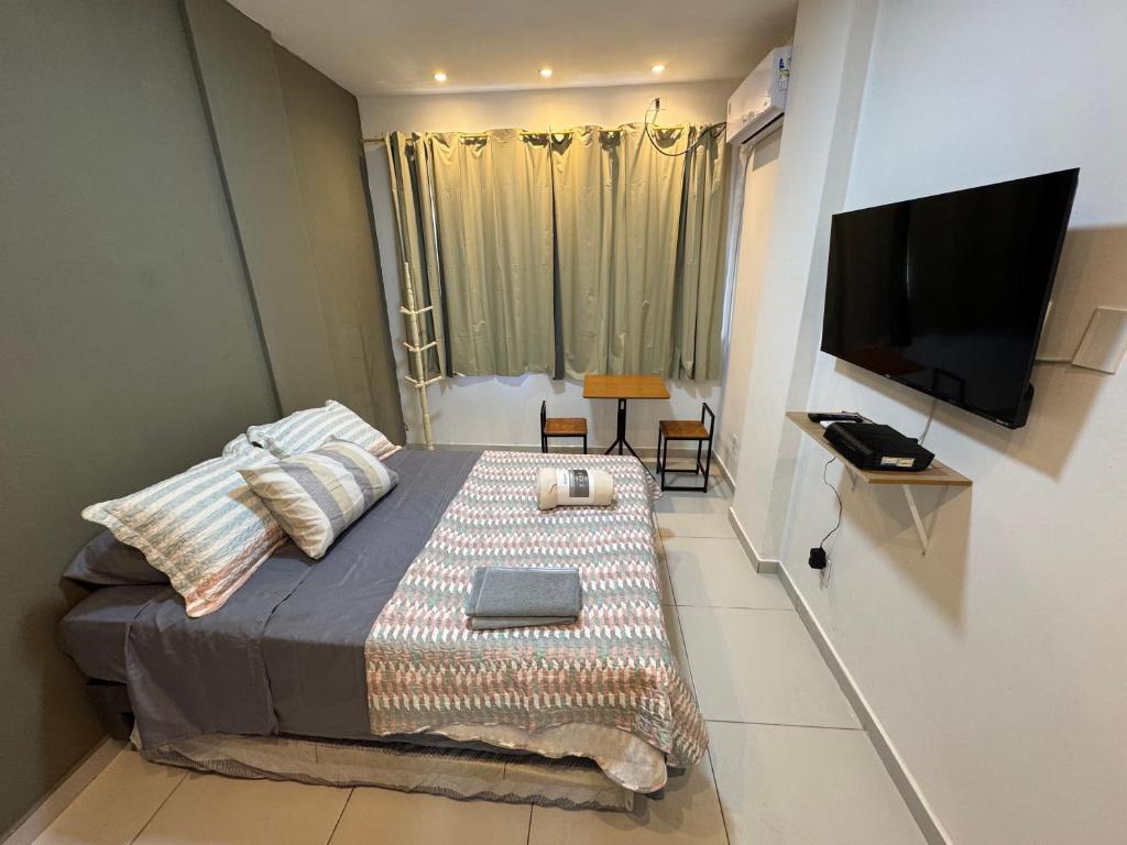 um pequeno quarto com uma cama e uma TV de tela plana em Copacabana Studio no Rio de Janeiro