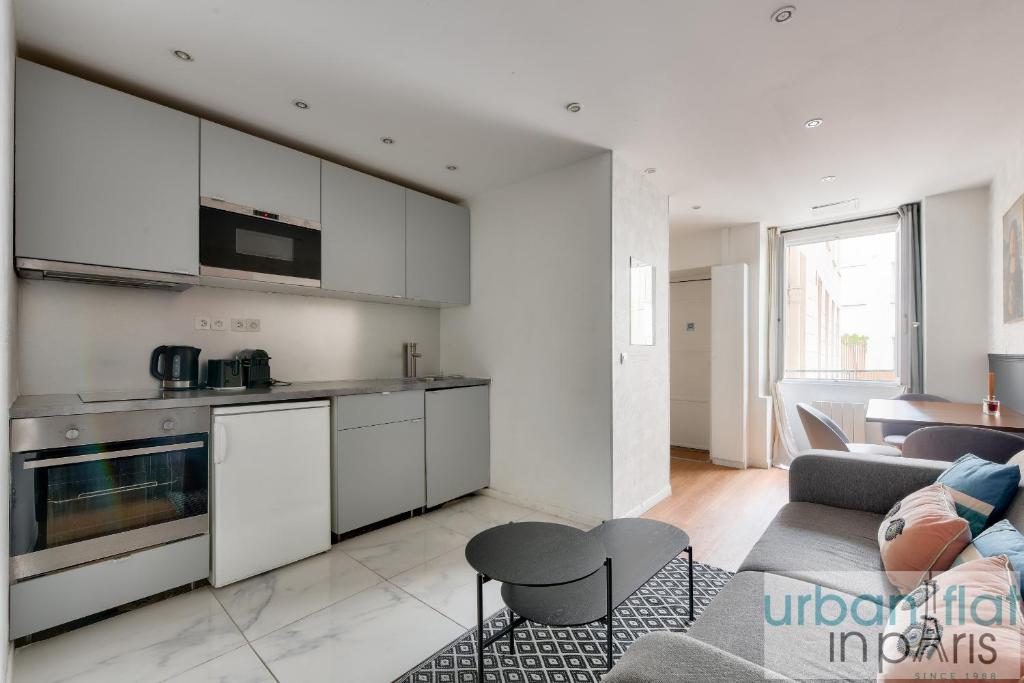 Il comprend une cuisine et un salon avec des placards blancs et un canapé. dans l'établissement 04 Best Flat Montorgeuil 3, à Paris