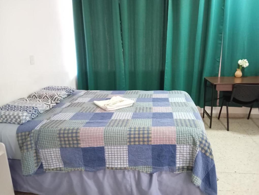 a bed with a blue and green quilt on it at Volcano Hostal y Restaurante in San Salvador