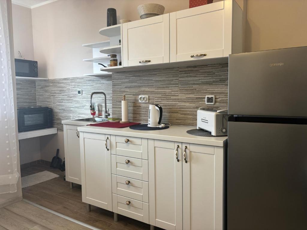 a kitchen with white cabinets and a black refrigerator at Red Square Apartment in Pirot