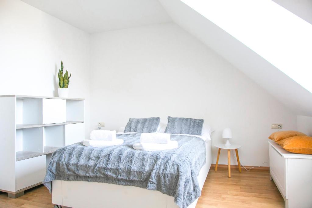 a white bedroom with a bed with a blue blanket at Charmantes Apartment mit Tiefgarage in Magdeburg