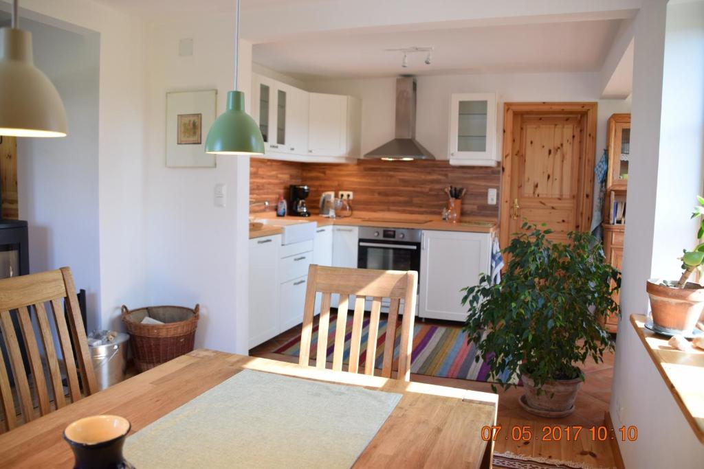 a kitchen with a dining table and a kitchen with white cabinets at "Lütt Huus" in Ostermarkelsdorf
