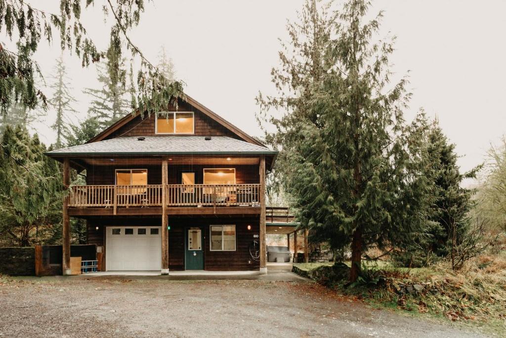 a large wooden house with a balcony and a tree at Mt, Baker Rim Cabin 77 - Hot Tub - Wi-Fi - Evc - Pets Ok - Views in Glacier