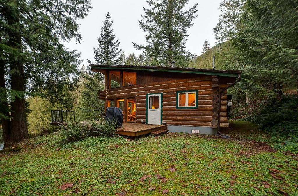 a small log cabin in the woods with a porch at Silver Lake Cabin #97 - Lakeside - Dock - Pets Ok in Maple Falls